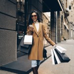 Shopping. Black Friday. Technology. Woman with shopping bags is using a smartphone and smiling while walking down the street