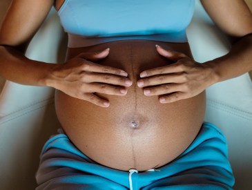 A pregnant woman touching her belly.