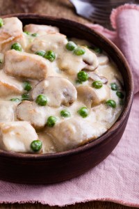 Homemade chicken and mushroom stew served in ceramic bowl on rustic wooden table
