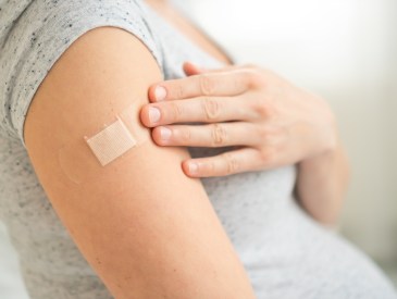 Vaccination of a pregnant woman. Close view of shoulder after vaccine injection with adhesive tape. Covid vaccination concept. Health and medicine during pregnancy.
