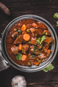 Beef stew with carrots, food photography, lot of herbs inside stew