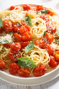 spaghetti with roasted cherry tomato and fresh basil in a white plate