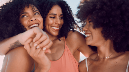 Black women holding hands and laughing